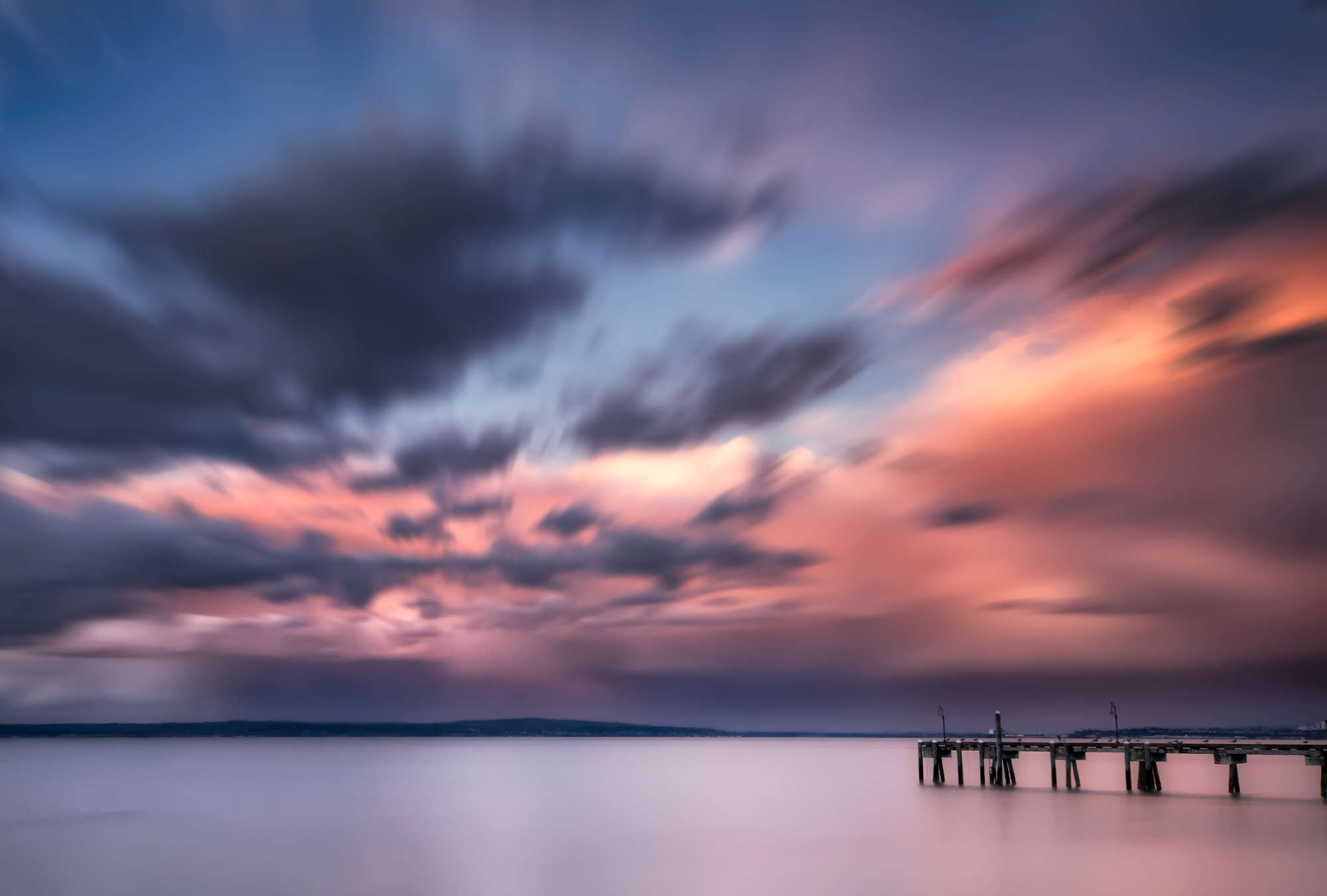             Photo wallpaper coastal landscape with jetty in the water and colourful clouds
        