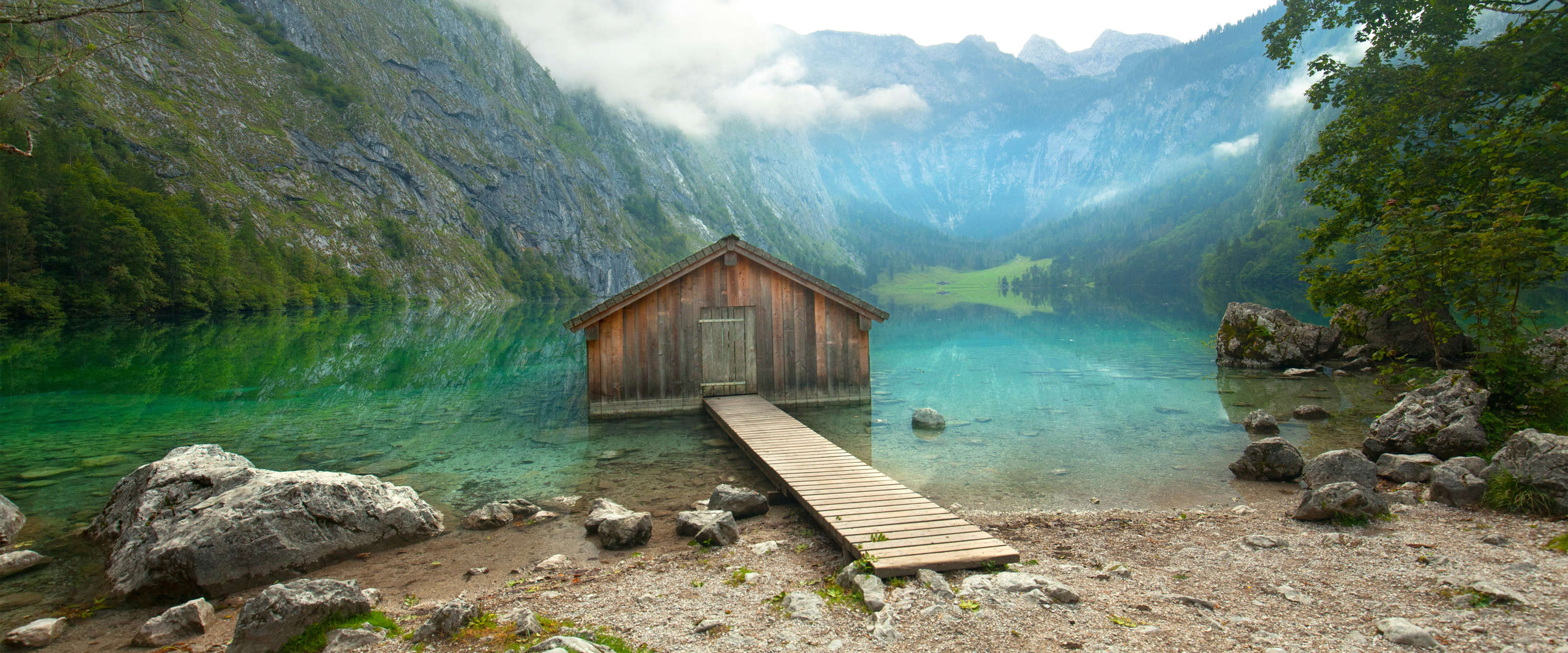             Papel pintado de Refugio de montaña y lago con pasarela de madera y panorama de la cumbre
        