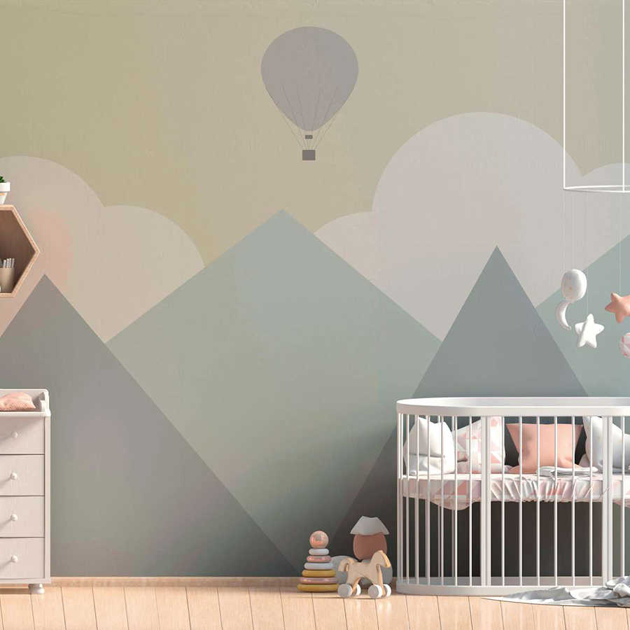 Papier peint panoramique chambre enfant Montagnes avec nuages et montgolfière - jaune, vert, gris
