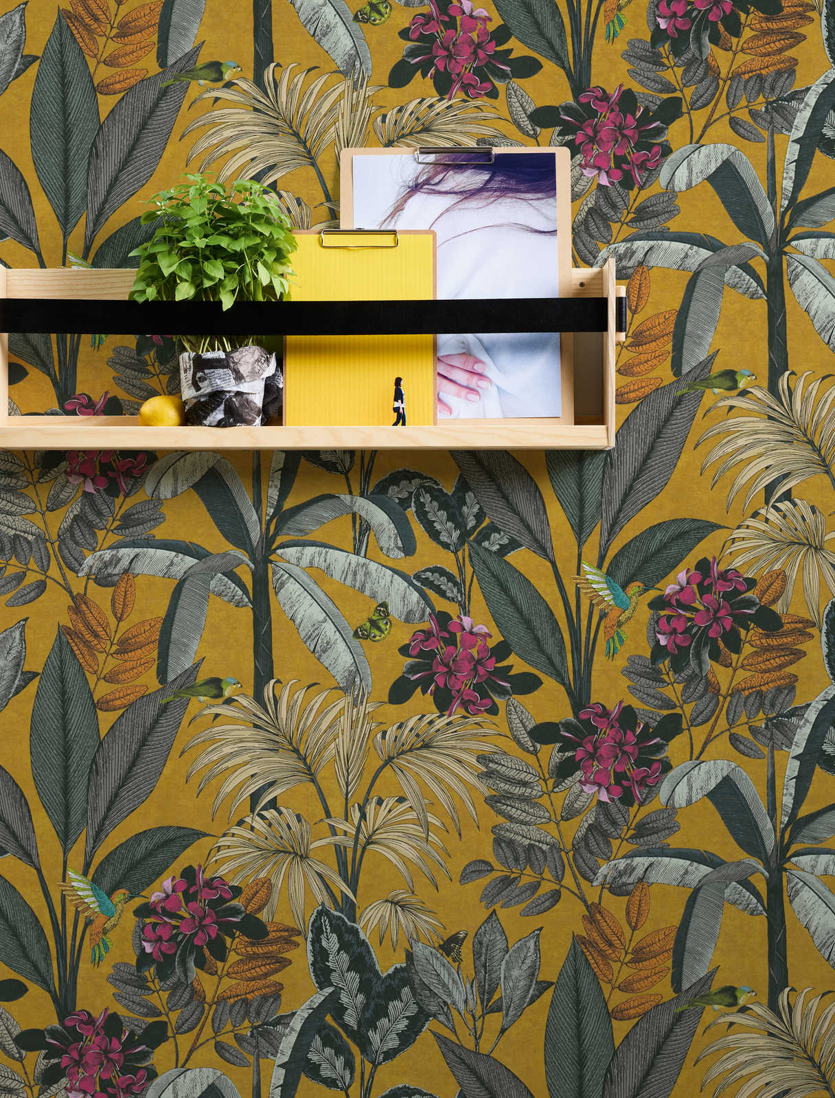             Papel pintado amarillo mostaza con hojas tropicales y motivos florales
        
