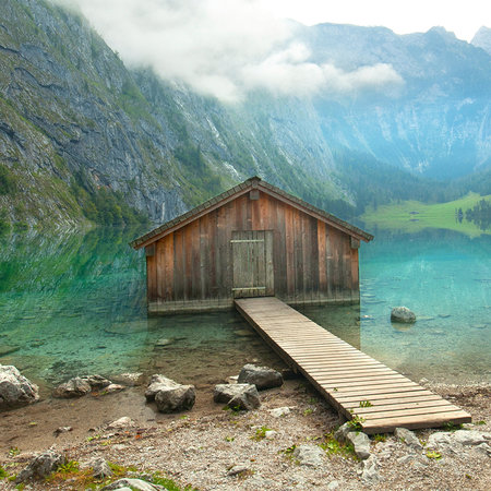 Photo wallpaper mountain hut & lake with wooden footbridge & summit panorama

